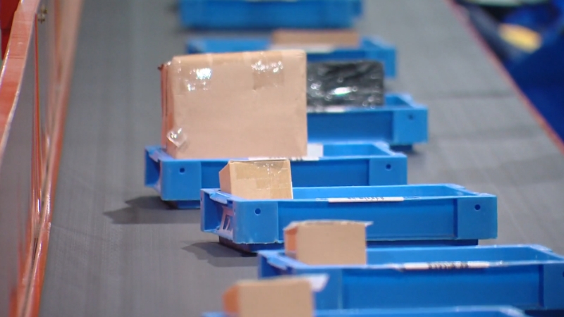 Packages on a conveyor belt inside a logistics warehouse, ready for distribution